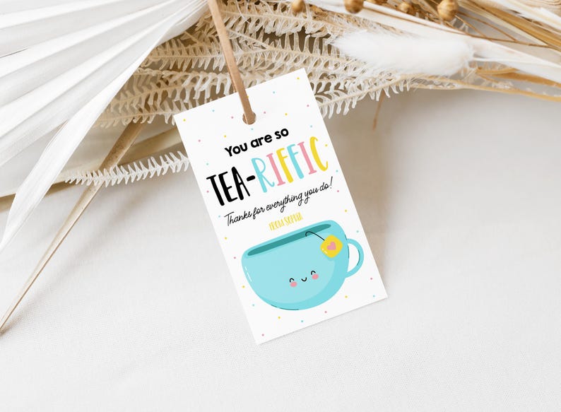 May include: A white card with blue, pink, and yellow text that reads "You are so TEA-RIFFIC! Thanks for everything you do!"  A blue teacup with a yellow flower and a smiling face is illustrated on the card.