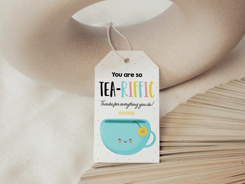 May include: A white gift tag with colorful text that reads "You are so TEA-RIFFIC! Thanks for everything you do!"  A blue teacup with a yellow flower and a smiling face is illustrated below the text.