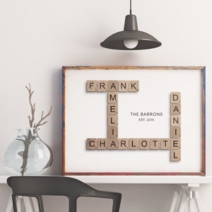 May include: A framed print with the names "Frank", "Mel", "Charlotte", and "Daniel" spelled out using wooden Scrabble tiles. The text "The Barrons Est. 2015" is printed below the names.