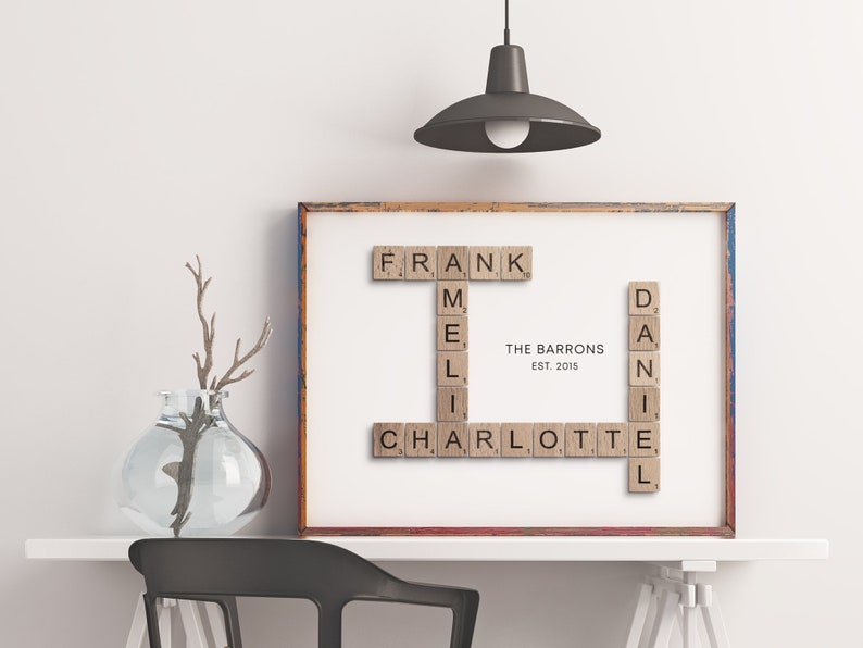 May include: A framed print with the names "Frank", "Mel", "Charlotte", and "Daniel" spelled out using wooden Scrabble tiles. The text "The Barrons Est. 2015" is printed below the names.