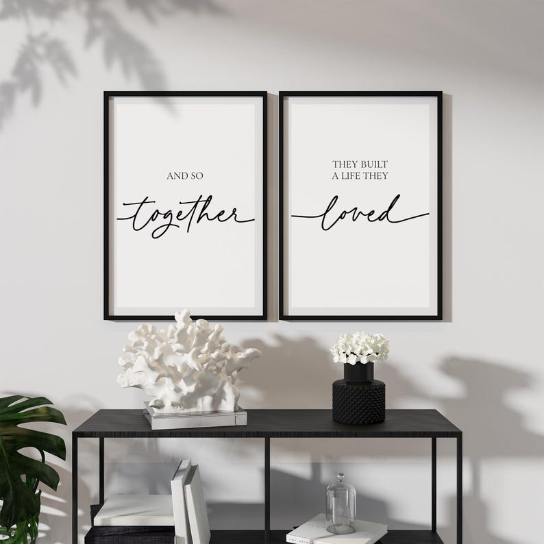 May include: Two black framed prints with white backgrounds and black calligraphy. The left print says "And so together". The right print says "They built a life they loved".