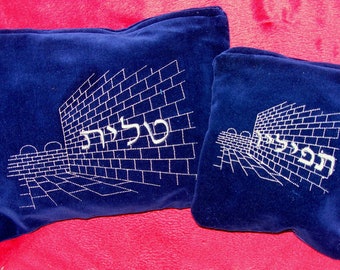 May include: Two blue velvet pillow covers with white embroidery. The larger pillow features a depiction of the Western Wall in Jerusalem with the Hebrew text "Kotel" embroidered on it. The smaller pillow features a similar depiction with the Hebrew text "HaKotel" embroidered on it.