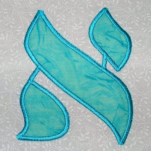 May include: A turquoise blue Hebrew letter 'nun' embroidered on a white fabric with a floral pattern.