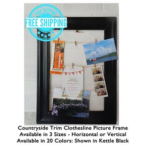 May include: Black rectangular picture frame with a clothesline design. The frame holds various photos and cards clipped to twine. The text on the frame reads "Countryside Trim Clothesline Picture Frame".