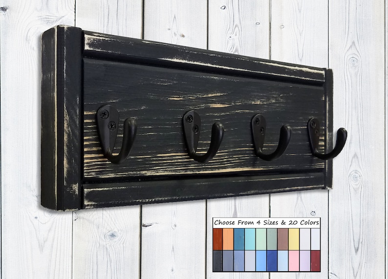 May include: A black wooden wall-mounted coat rack with four black metal hooks. The wood has a distressed finish, with visible grain and a slightly worn appearance. The image includes a color palette with options for sizes and colors.
