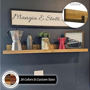 May include: A wooden shelf with a dark gray background. The shelf is decorated with a coffee pot, a small vase with flowers, and two framed signs. One sign reads "Mangia & Statti" and the other sign reads "Break in Case of Emergency". The shelf is handmade in Pennsylvania and is available in 20 colors and custom sizes.