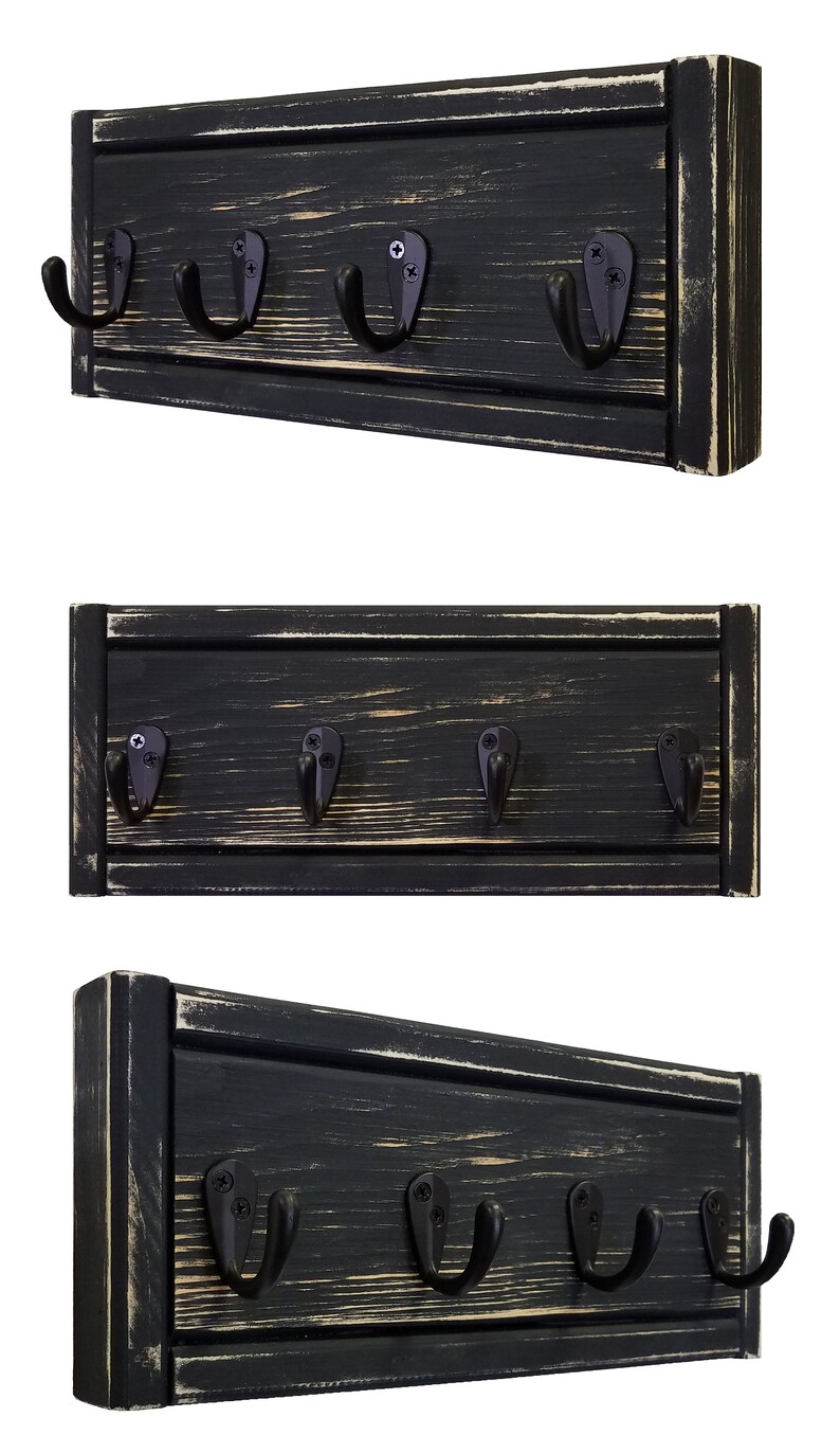 May include: A black wooden wall-mounted coat rack with five black metal hooks. The wood has a distressed finish with visible grain and light-colored accents. The hooks are attached with screws.