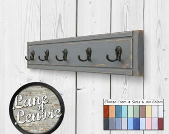 May include: A grey wooden coat rack with five black metal hooks. The rack is mounted on a white wooden wall. The image includes a logo that says "Lane of Lenore" and a colour chart.