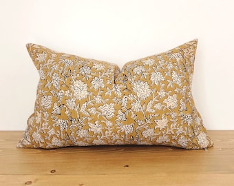 May include: A mustard yellow throw pillow with a white and black floral pattern.