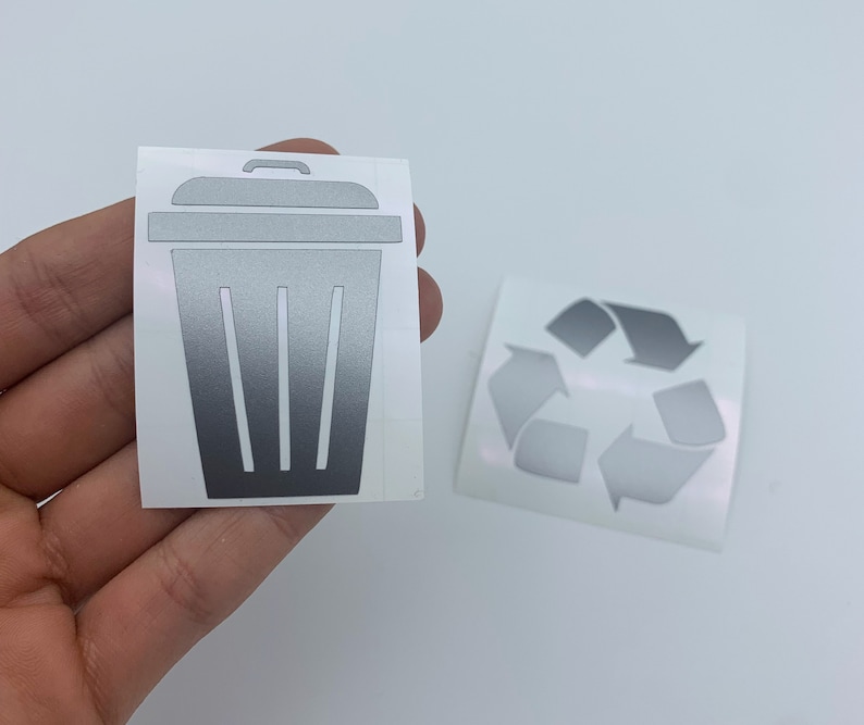 May include: Two silver vinyl stickers, one with a trash can icon and the other with a recycling symbol.