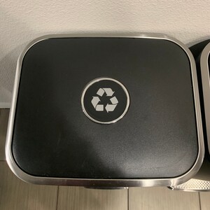 May include: A silver and black recycling bin with a recycle symbol on the lid.