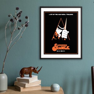 May include: A black and white poster with a red and orange graphic of a man holding a knife. The text on the poster reads "A bit of the old ultra-violence" and "Clockwork Orange".