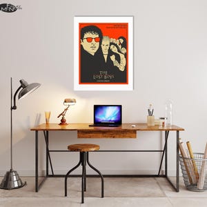 Puede incluir: Un p&oacute;ster minimalista con fondo rojo que presenta una ilustraci&oacute;n en blanco y negro de los personajes principales de la pel&iacute;cula "The Lost Boys". El t&iacute;tulo de la pel&iacute;cula est&aacute; escrito en letras doradas debajo de la ilustraci&oacute;n.