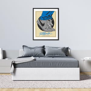 May include: A minimalist poster with a black frame featuring a pair of grey sneakers with blue laces and the word "Footloose" in blue text.