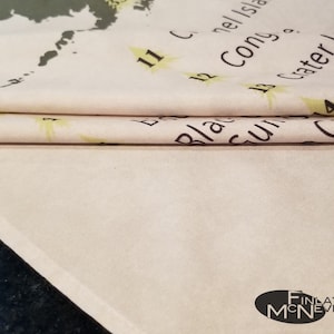 May include: A close-up of a folded white fabric with black text that reads "11 C. Connell Island", "12 Cong. o.", "13 Crater Lake", and "14 C", with a yellow star next to each number. The fabric has a light brown background and a white border.