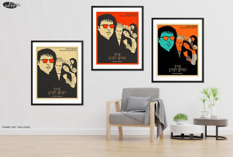 Puede incluir: Tres carteles de cine enmarcados para la pel&iacute;cula "The Lost Boys". Cada cartel presenta un grupo diferente de personajes de la pel&iacute;cula, incluyendo un vampiro con gafas de sol rojas y un vampiro con gafas de sol azules. Los carteles est&aacute;n colocados contra una pared blanca con un sill&oacute;n gris y dos mesas auxiliares.