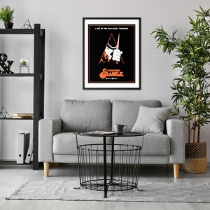 May include: A black and white movie poster for the film "A Clockwork Orange" featuring a man in a white shirt and black hat holding a knife. The poster has a red and orange triangle in the background.