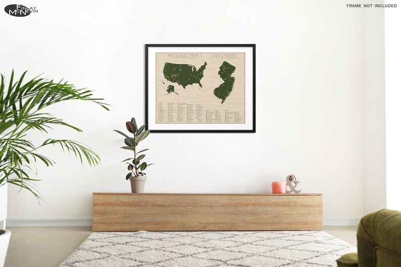 May include: A framed map of the United States with all the national parks marked in green. The map is on a white wall above a wooden shelf with a plant and decorative objects.