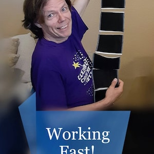 May include: A person in a purple t-shirt holding a strip of black objects. The shirt has a graphic with text and a star. The image has the text "Working Fast!" in a blue banner.