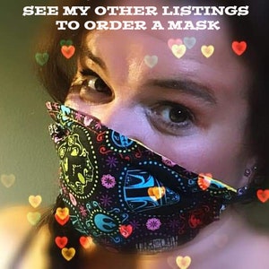 May include: A black face mask with a colorful Day of the Dead sugar skull design. The mask has a repeating pattern of skulls, flowers, and other decorative elements in various colors. The text "SEE MY OTHER LISTINGS TO ORDER A MASK" is visible.