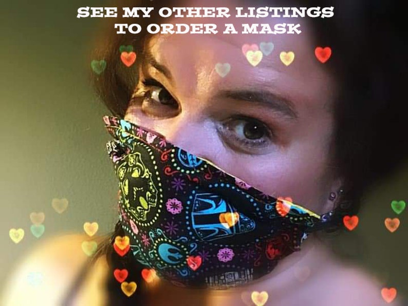 May include: A black face mask with a colorful Day of the Dead sugar skull design. The mask has a repeating pattern of skulls, flowers, and other decorative elements in various colors. The text "SEE MY OTHER LISTINGS TO ORDER A MASK" is visible.