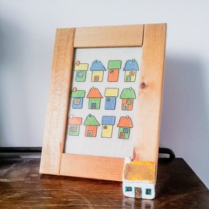 embroidered and framed modern cross stitch coloured cottages cross stitch