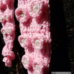 May include: Pink crocheted octopus with white centers on the tentacles. The octopus is crocheted in a single crochet stitch.