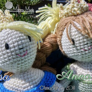 May include: Two crocheted dolls, Elsa and Anna, from the movie Frozen, wearing crowns and dresses. The dolls are made with white yarn and have black eyes and pink lips. The dolls are sitting on a green surface.