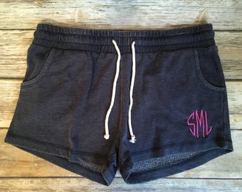 Puede incluir: Shorts de algodón azul oscuro con cordón blanco y un monograma bordado en rosa "SML" en la pierna derecha.