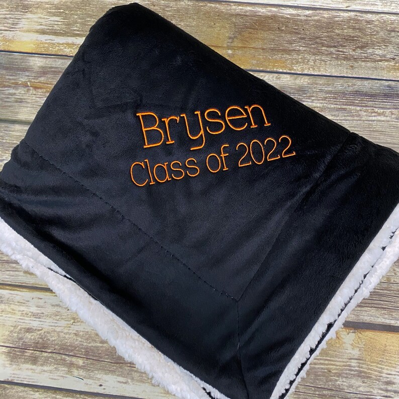 May include: Black and white fleece blanket with orange embroidery that reads "Brysen Class of 2022".