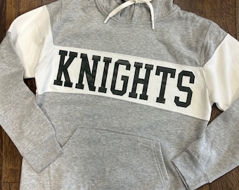 May include: Gray hooded sweatshirt with white trim and the word "KNIGHTS" printed in black letters.