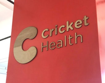 May include: A red wall with a wooden sign that says "Cricket Health" with a stylized wooden "C" to the left of the text.