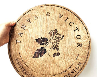 May include: A round wooden sign with the text "Tanya & Victor Photography & Design" and a floral design in the center.