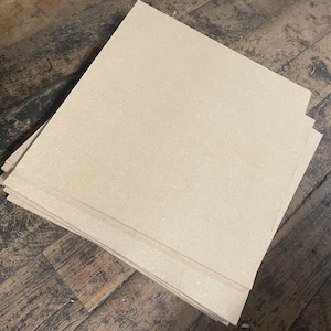 May include: A stack of beige cardboard sheets, likely for crafting or other DIY projects.