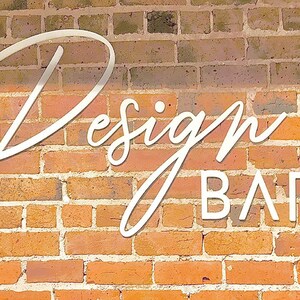 K&ouml;nnte beinhalten: Ein wei&szlig;es Schild mit dem Text "Design BAR" an einer Backsteinwand.