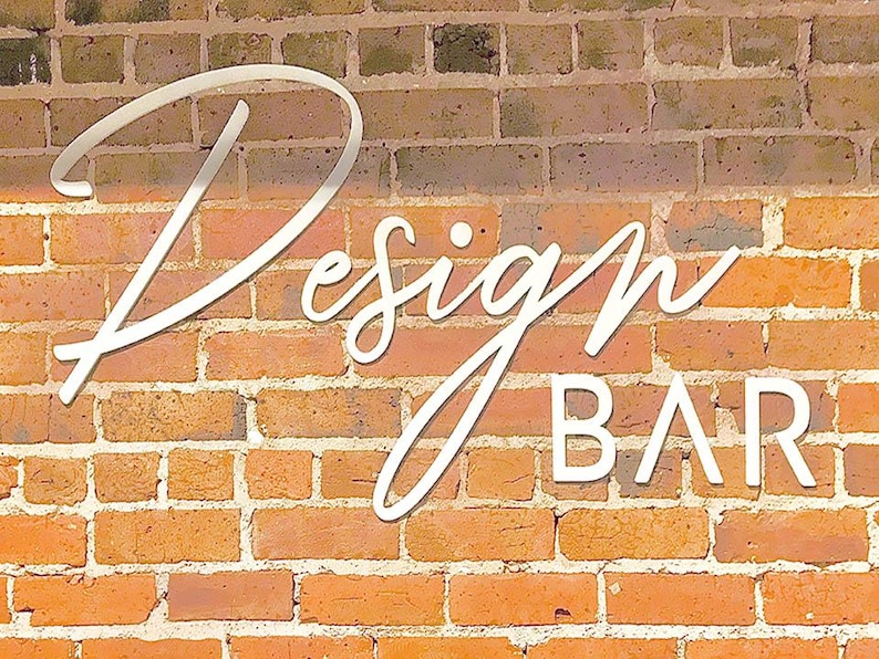 K&ouml;nnte beinhalten: Ein wei&szlig;es Schild mit dem Text "Design BAR" an einer Backsteinwand.