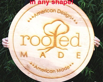 May include: A round wooden sign with the text "...American Design..." and "...American Made..." around the edge. The center of the sign features a stylized tree with roots and the word "rooted" in a circle around the tree. The text "MADE" is below the tree.