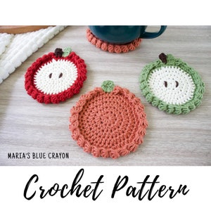 May include: Three crocheted apple-shaped coasters in red, green, and orange. The coasters have a white center and a scalloped edge.