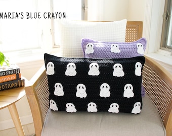 Peut inclure: Un fauteuil en osier avec deux coussins blancs et un coussin crocheté noir et blanc avec un motif de fantôme. Le coussin porte le texte "MARIA'S BLUE CRAYON".