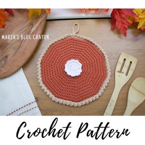May include: A handmade, round, crochet potholder in shades of orange, beige, and white, resembling a pie. The potholder has a loop for hanging and is surrounded by fall-themed decorations. The text "Crochet Pattern" is at the bottom.
