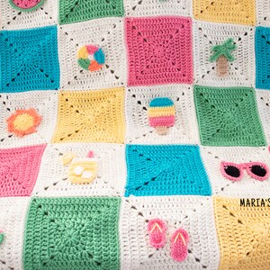 May include: A colourful crochet blanket with a summer theme. The squares are crocheted in different colours and feature various summer-themed appliques, including a watermelon, sunglasses, a beach ball, a palm tree, a popsicle, a sun, a pineapple, flip-flops, and a drink with an umbrella. The blanket is made with white, yellow, pink, blue, and green yarn.