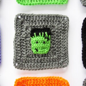 May include: A gray crochet square with a green Frankenstein face in the center. The square is surrounded by other squares in different colors, including purple, green, black, orange, and gray.