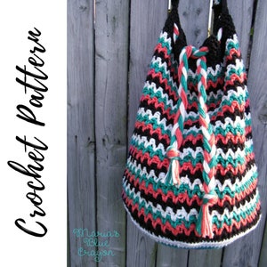 May include: A crocheted tote bag with a black, white, coral, and teal chevron pattern. The bag has a braided handle with tassels.