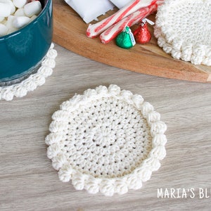 May include: Three white crocheted coasters with a raised edge. The coasters are on a wooden surface.