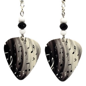 May include: A pair of silver earrings with black and white beads and guitar pick-shaped charms featuring a black and white musical note pattern.