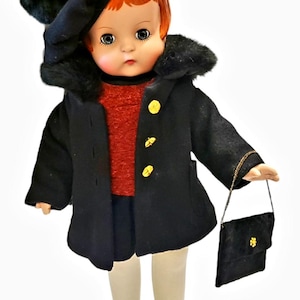 Puede incluir: Una muñeca vintage vestida con un abrigo negro con cuello de piel sintética, un sombrero a juego y un pequeño bolso. La muñeca tiene el pelo rojo, un suéter rojo y zapatos negros. Botones dorados adornan el abrigo. La muñeca lleva medias blancas.