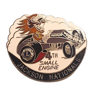 May include: A vintage pin featuring a race car with a roaring lion mascot. The pin is in shades of brown, black, and white, with the text "4th Small Engine Nationals" and "Jackson, MN". The pin is oval-shaped.
