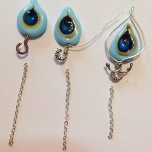 Pu&ograve; includere: Tre paia di orecchini con perline di vetro blu e oro a forma di occhio di pavone. Due paia hanno un semplice anello di filo e il terzo paio ha un design di filo pi&ugrave; elaborato.