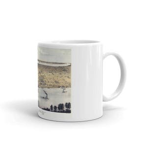 May include: White ceramic coffee mug with a vintage illustration of a city skyline. The illustration is in shades of brown, beige, and gray. The mug has a black handle.
