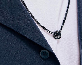 May include: A black chain necklace with a round pendant featuring the text "CHRISTIAN"
